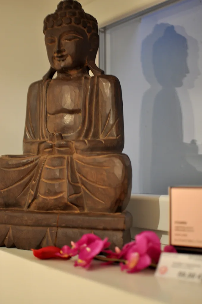 Buddhafigur und Blütendekoration im Kosmetikbereich